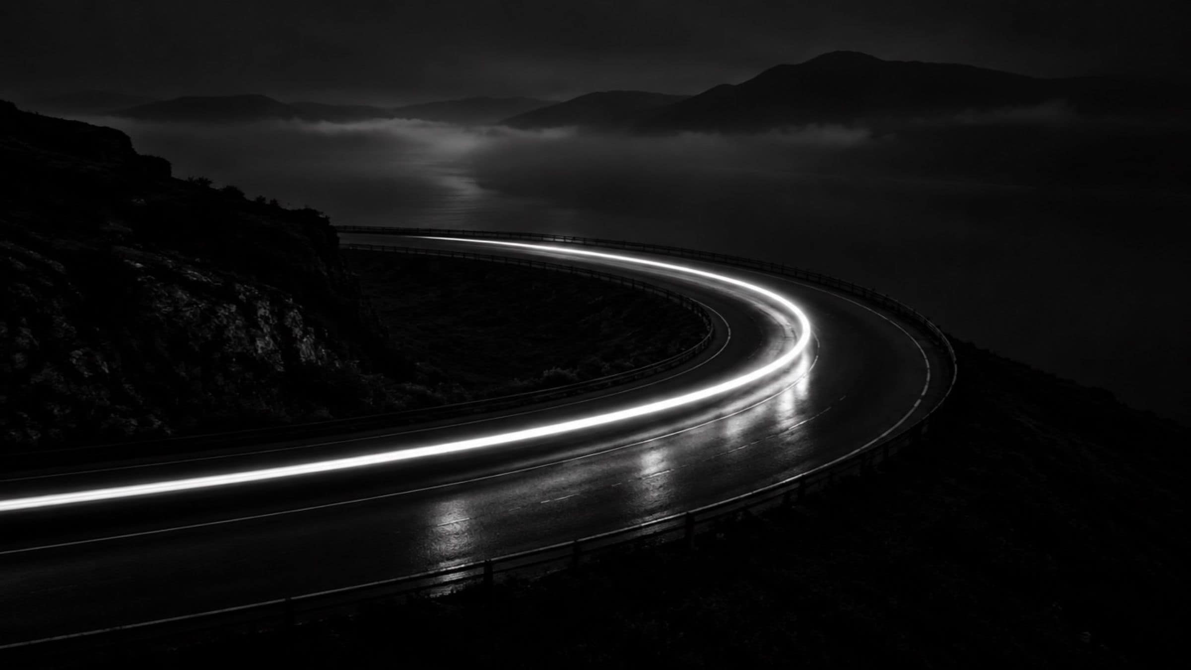Scia di luce che disegna una curva di asfalto nella notte