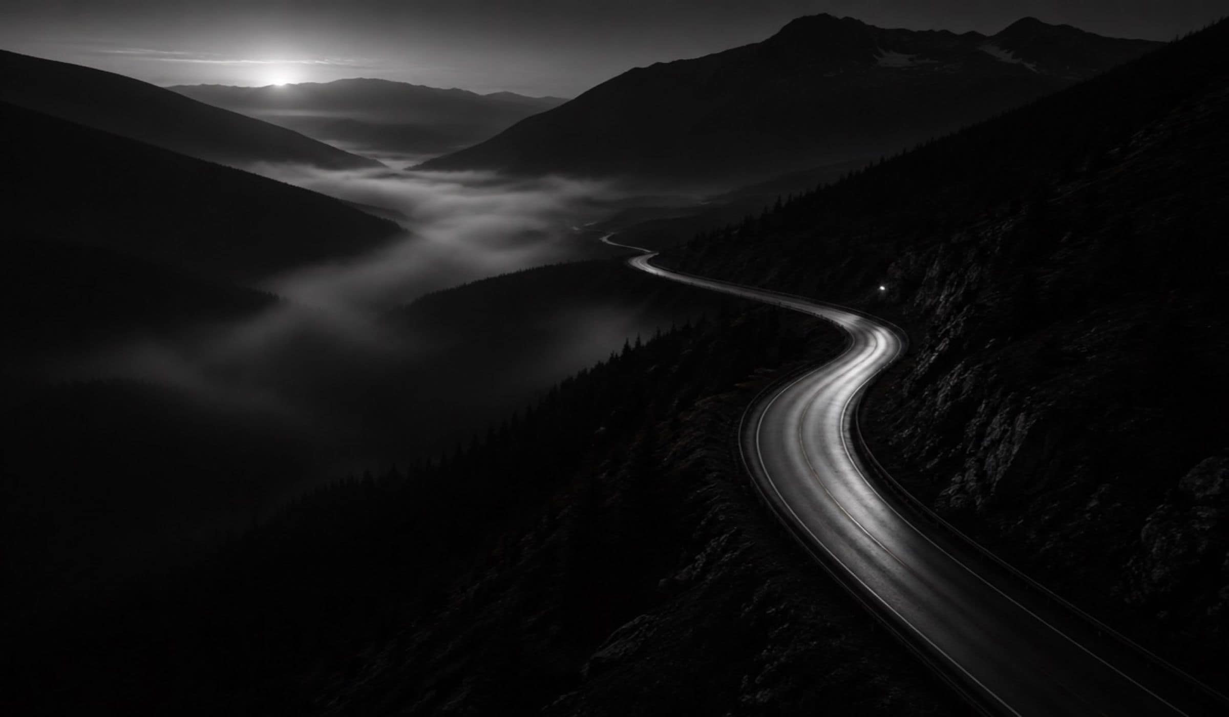 Strada di montagna che scende verso una valle nella foschia, all’alba
