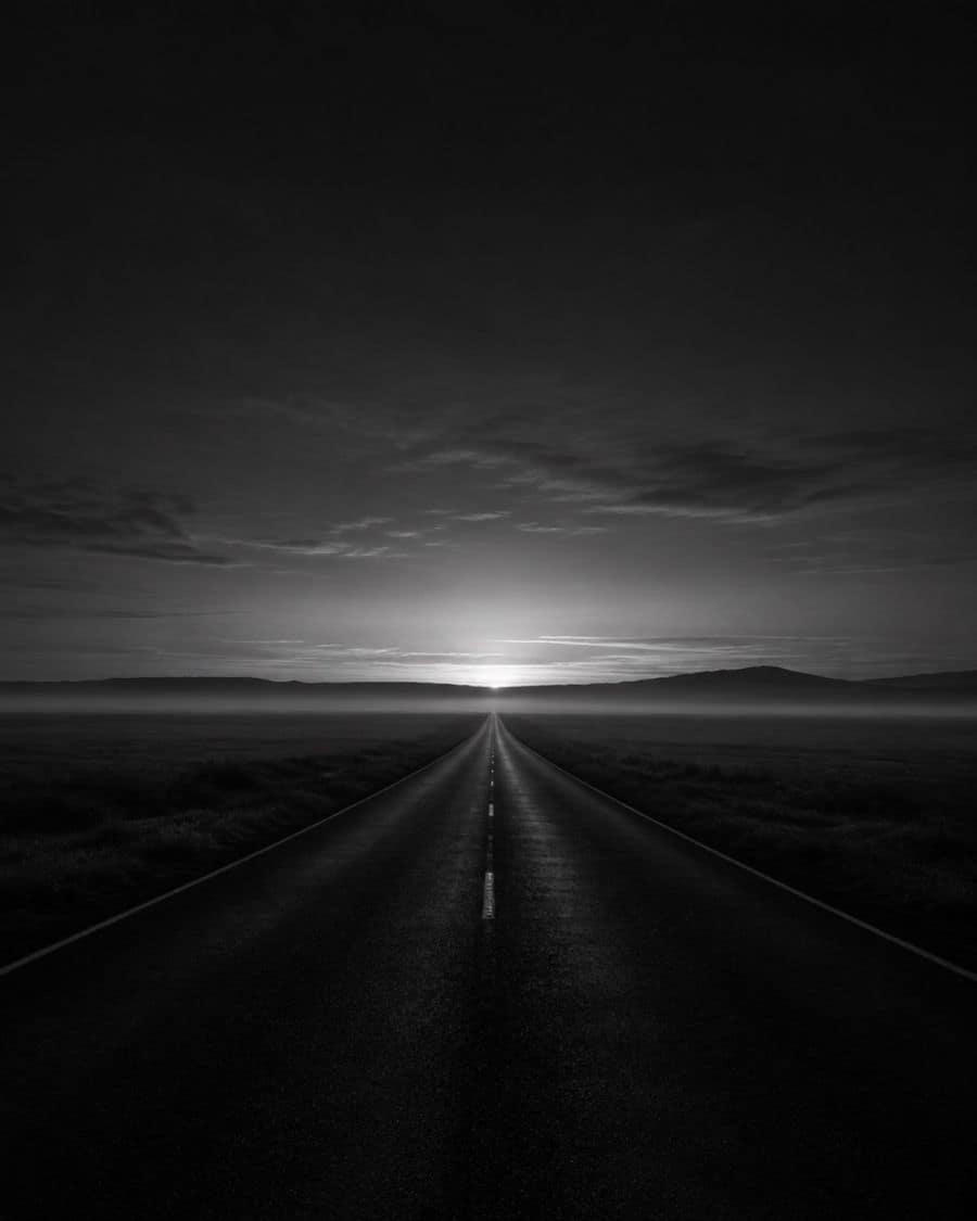 Strada dritta che corre verso l’orizzonte alle prime luci